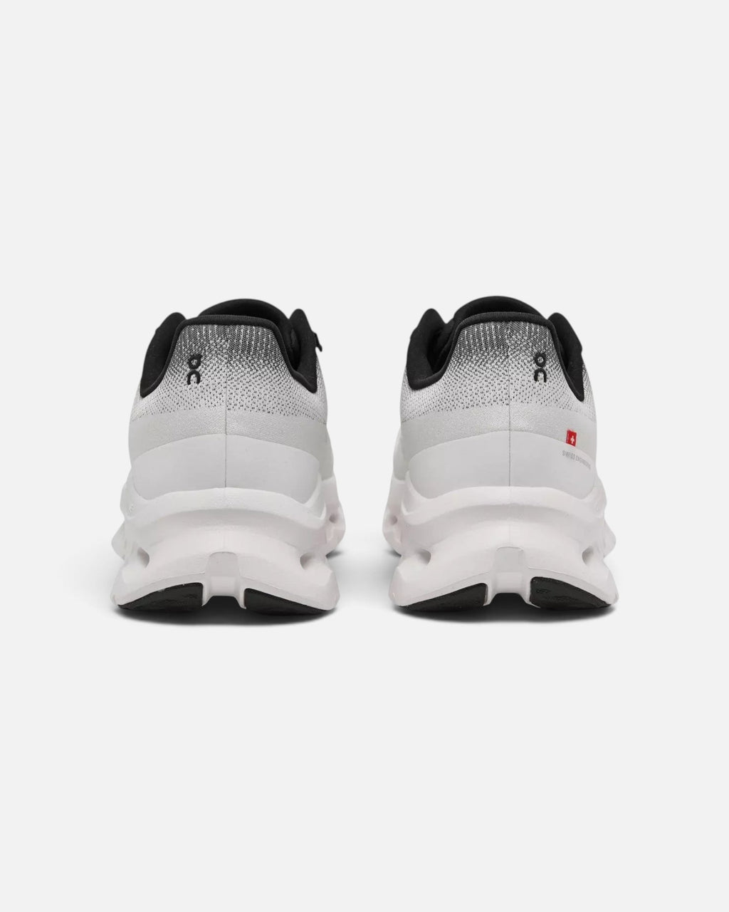 CRIUW On Cloudtilt sneakers in black and ivory, showing the rear view of the cushioned performance soles.