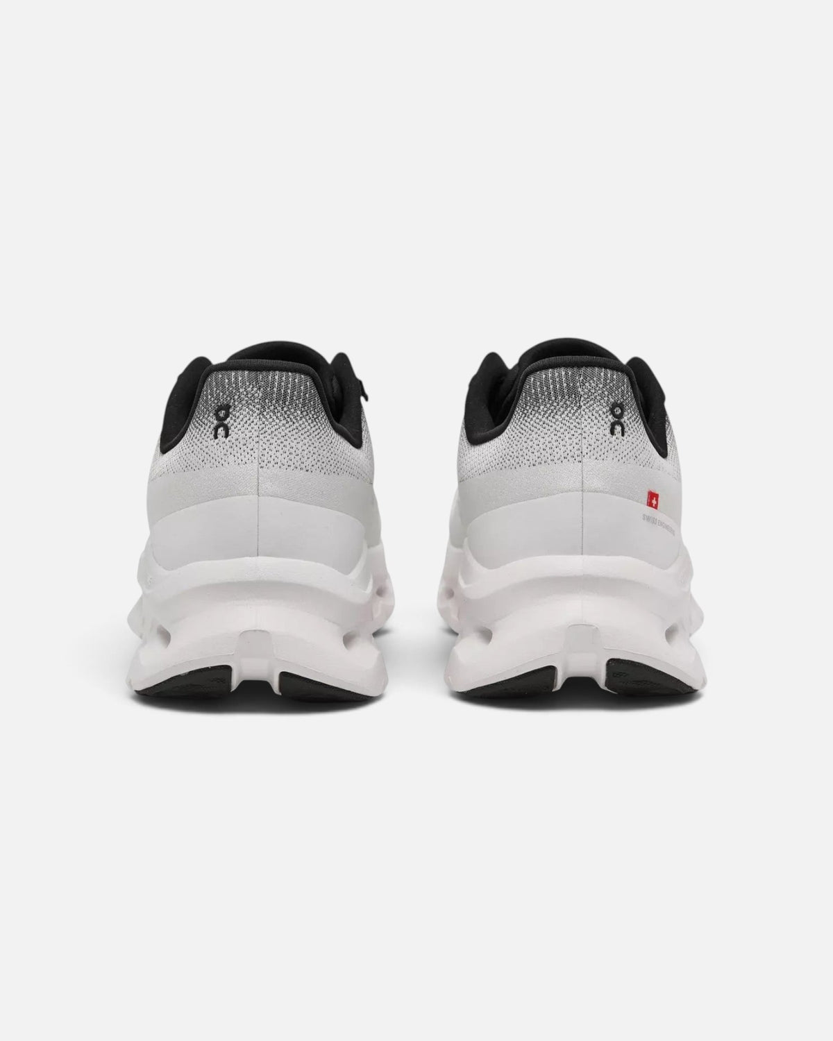 CRIUW On Cloudtilt sneakers in black and ivory, showing the rear view of the cushioned performance soles.